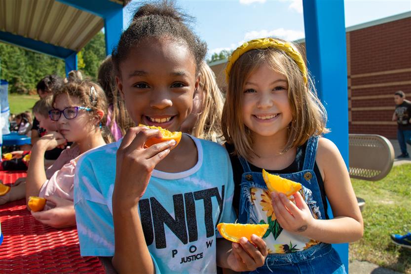 Two girls hold up orange slices